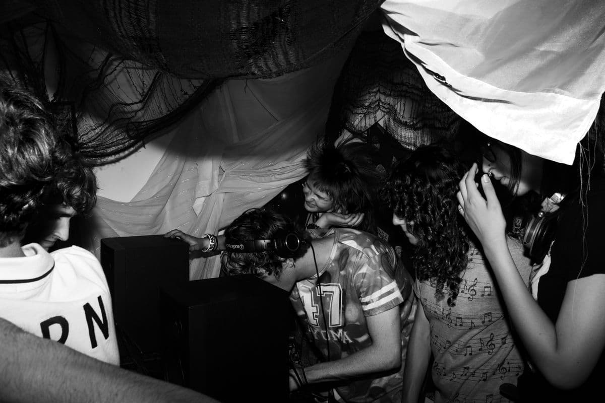 Black-and-white Elliot Mairet photograph of people gathered beneath fabric